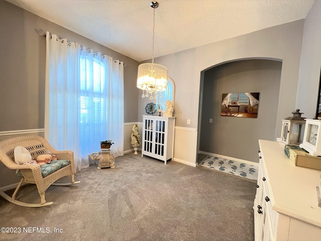 living area with a textured ceiling, carpet, baseboards, and an inviting chandelier