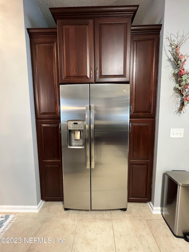 kitchen with light tile patterned floors, baseboards, dark brown cabinets, and stainless steel fridge with ice dispenser