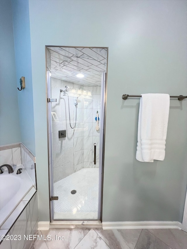 full bathroom featuring a stall shower, a garden tub, and baseboards