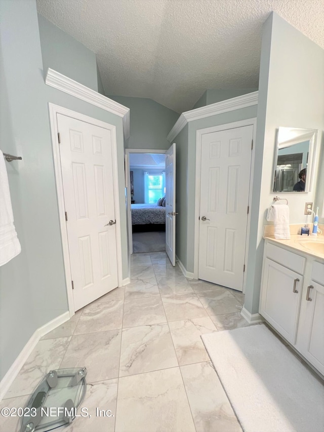 bathroom featuring marble finish floor, ensuite bathroom, vaulted ceiling, vanity, and a textured ceiling