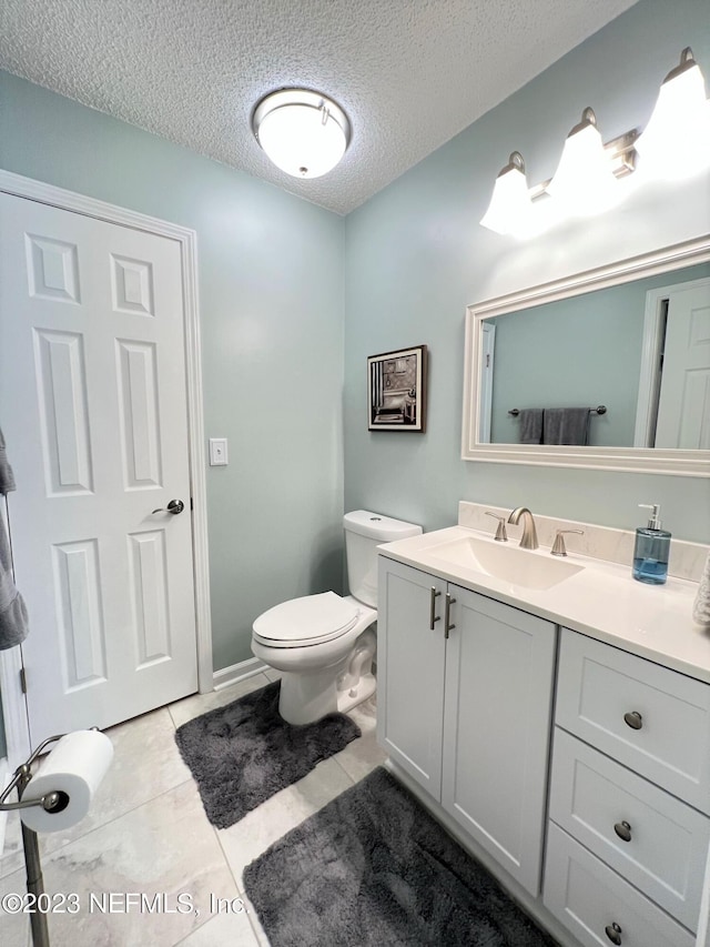 bathroom with tile patterned floors, a textured ceiling, toilet, and vanity