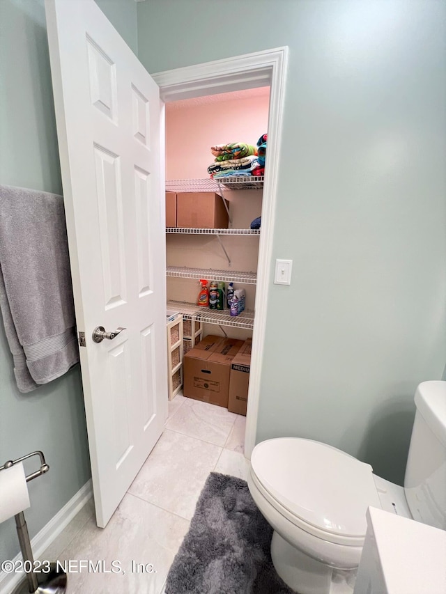 bathroom featuring toilet, baseboards, and tile patterned floors