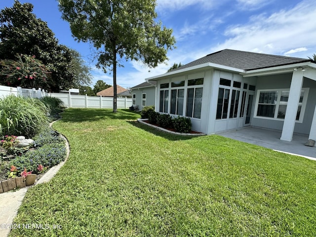 view of yard featuring a sunroom, a patio area, and fence