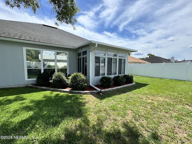 rear view of house with a shingled roof, fence, and a yard