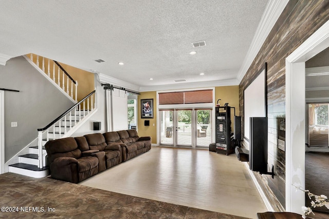 living room with a barn door, crown molding, and a textured ceiling