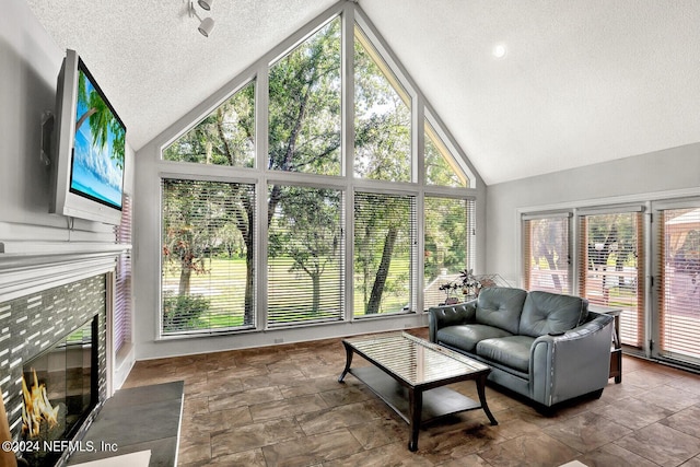 sunroom / solarium with a tile fireplace, lofted ceiling, and a healthy amount of sunlight