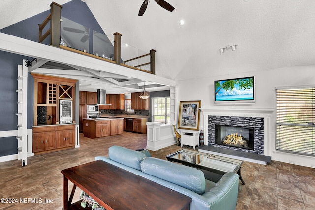 living room featuring a stone fireplace, ceiling fan, and a textured ceiling