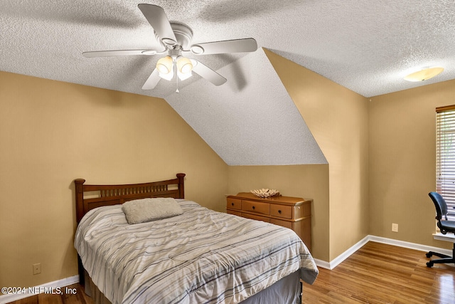 bedroom featuring a textured ceiling, ceiling fan, wood-type flooring, and lofted ceiling