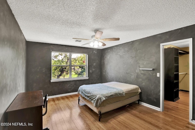 bedroom with hardwood / wood-style flooring, ceiling fan, and a textured ceiling