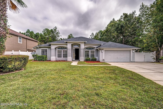 single story home featuring driveway, a garage, stucco siding, fence, and a front yard