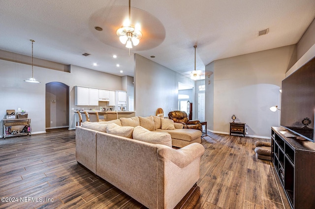 living room with visible vents, arched walkways, and dark wood-type flooring