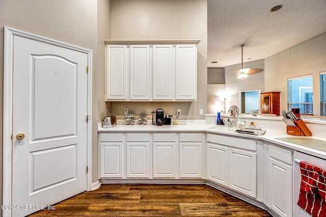 kitchen featuring white cabinets, dark wood-style floors, light countertops, a textured ceiling, and a sink