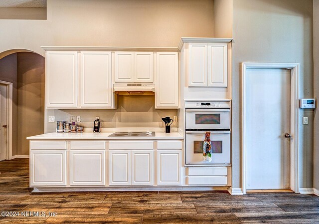 kitchen featuring double oven, custom exhaust hood, white cabinets, and dark hardwood / wood-style floors