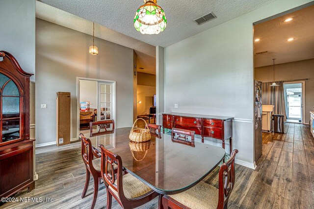 dining space featuring visible vents, a textured ceiling, baseboards, and wood finished floors