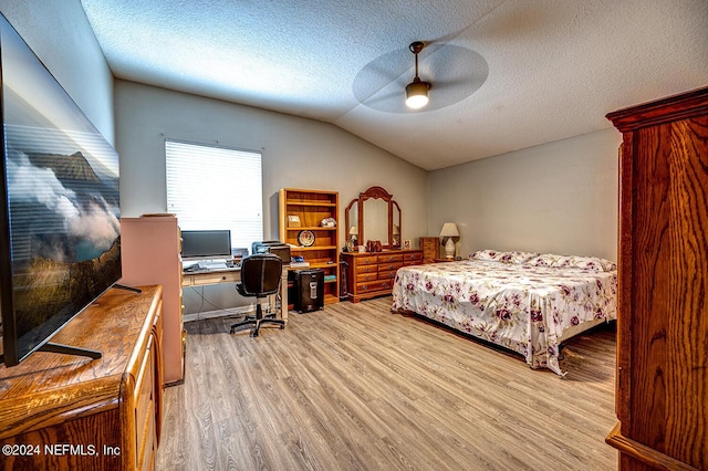 bedroom featuring lofted ceiling, light wood-style floors, ceiling fan, and a textured ceiling