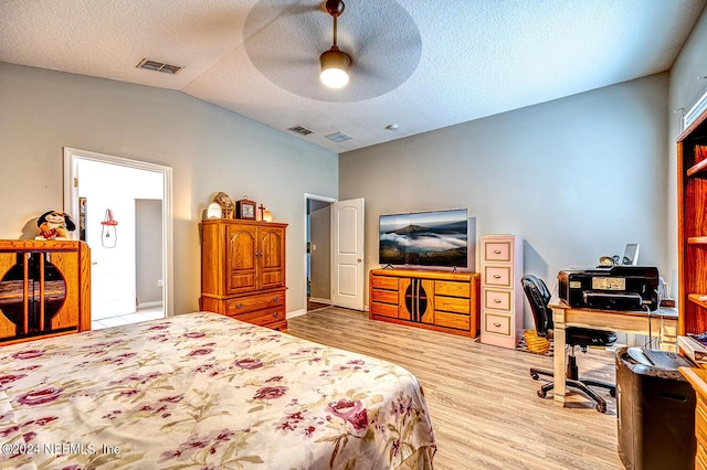 bedroom featuring lofted ceiling, visible vents, a textured ceiling, and wood finished floors