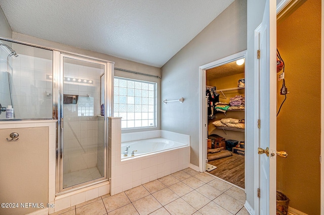 full bathroom with a shower stall, a spacious closet, a textured ceiling, and tile patterned floors