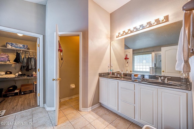 full bath featuring double vanity, a stall shower, a sink, and tile patterned floors