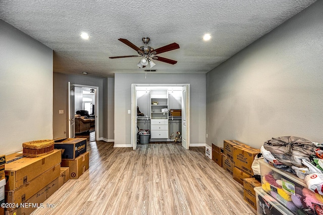 miscellaneous room with a textured ceiling, a ceiling fan, baseboards, visible vents, and light wood-style floors