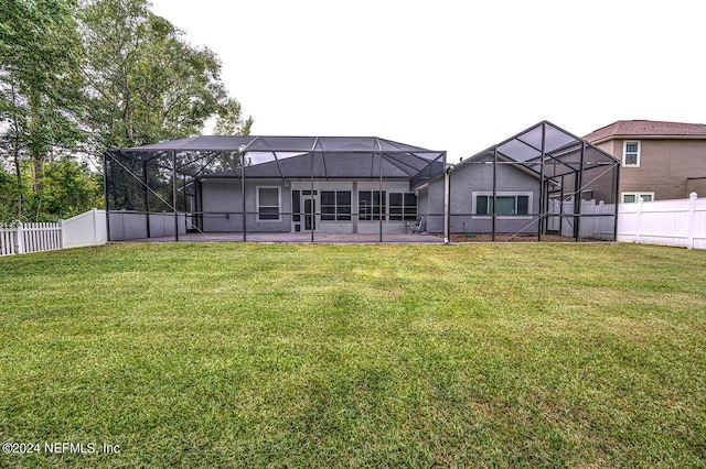 rear view of house featuring a lawn, a patio area, a fenced backyard, and a lanai