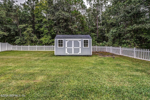 view of yard with a fenced backyard, a storage unit, and an outdoor structure