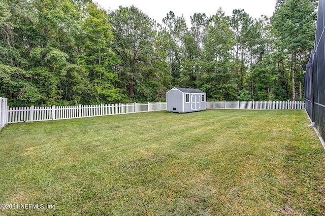 view of yard featuring an outbuilding, a fenced backyard, and a shed