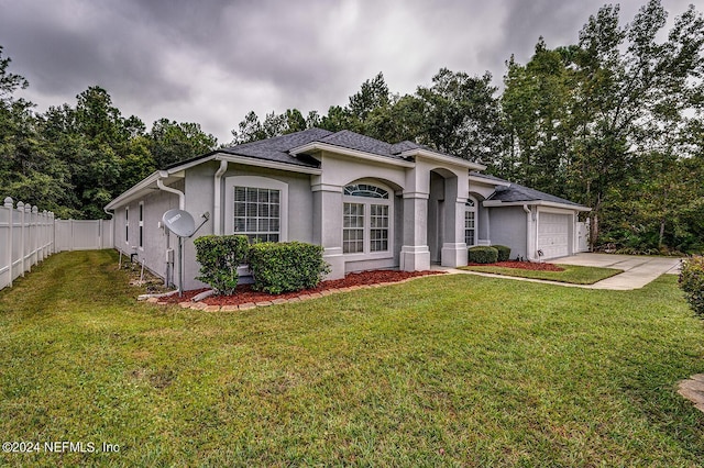 view of front facade with driveway, a garage, fence, a front lawn, and stucco siding