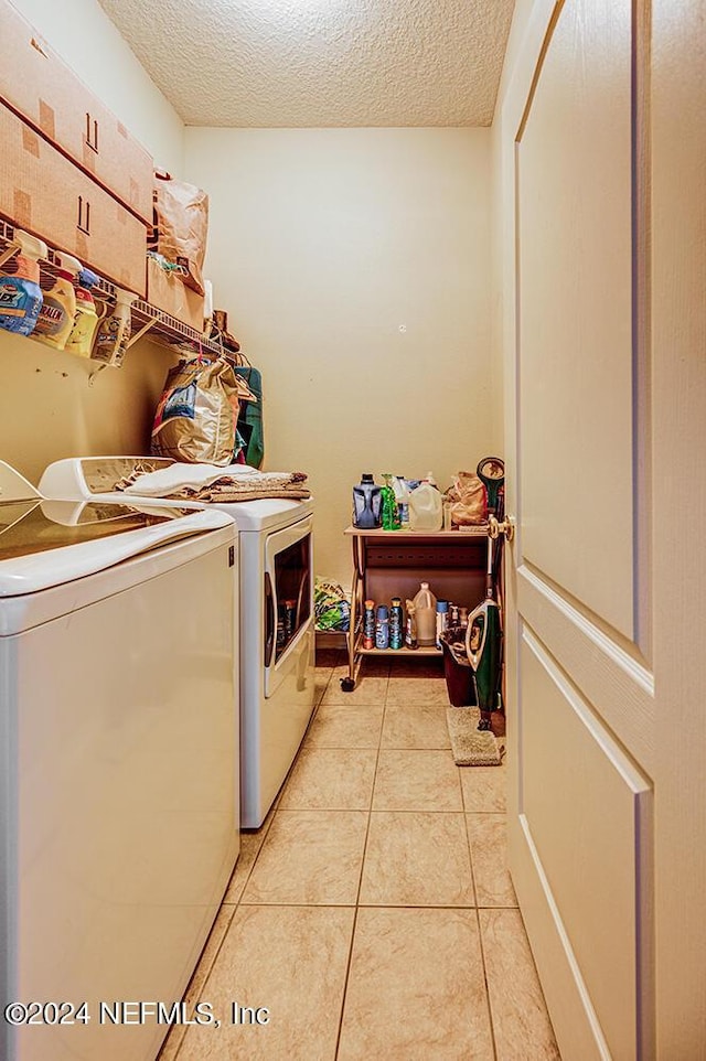 laundry room with light tile patterned floors, laundry area, washer and clothes dryer, and a textured ceiling