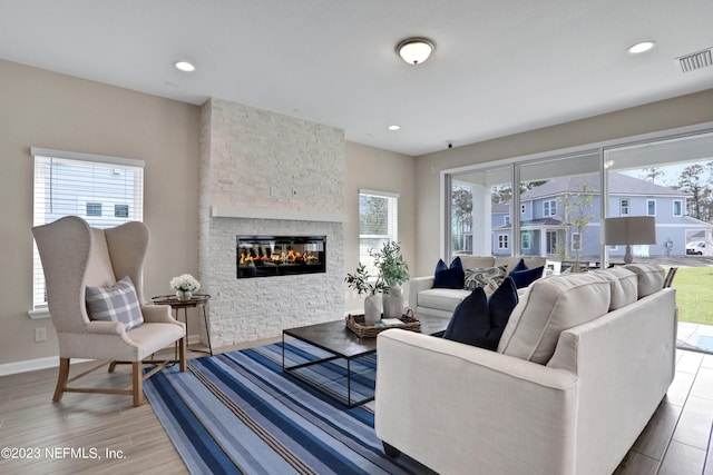 living room with plenty of natural light and a stone fireplace