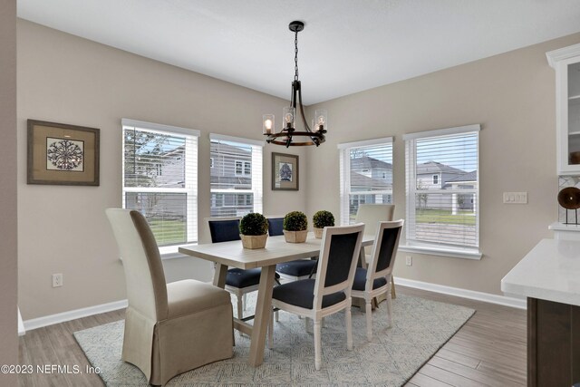 dining area with an inviting chandelier, wood-type flooring, and plenty of natural light