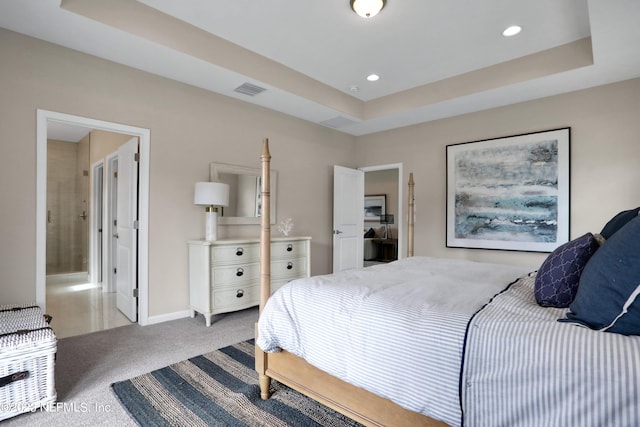 carpeted bedroom with connected bathroom and a raised ceiling