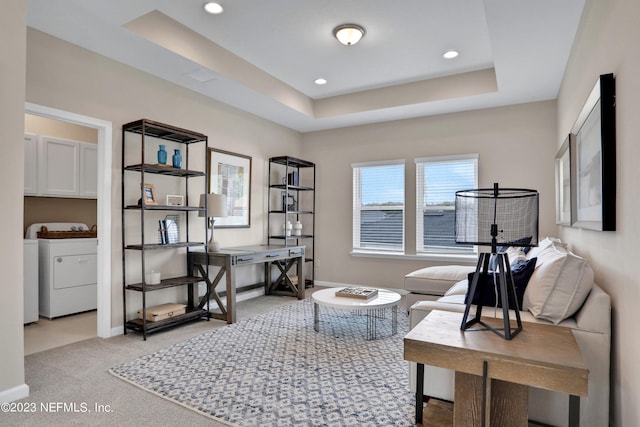 carpeted office featuring a raised ceiling and washing machine and clothes dryer