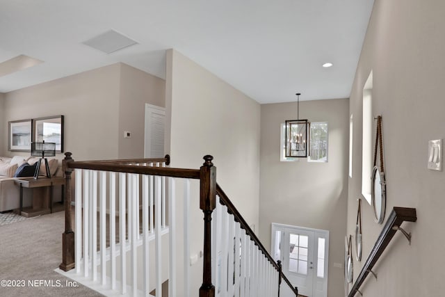 stairway with an inviting chandelier and carpet flooring