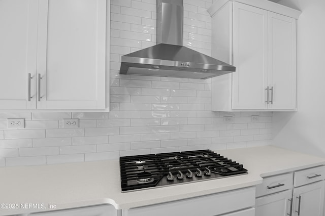 kitchen with white cabinetry, stainless steel gas cooktop, backsplash, and wall chimney exhaust hood