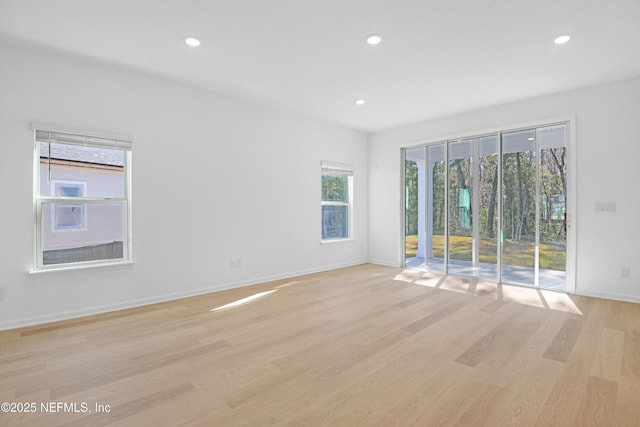 empty room featuring a healthy amount of sunlight and light hardwood / wood-style floors