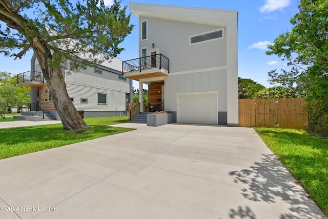 contemporary home featuring a balcony, a front lawn, and a garage