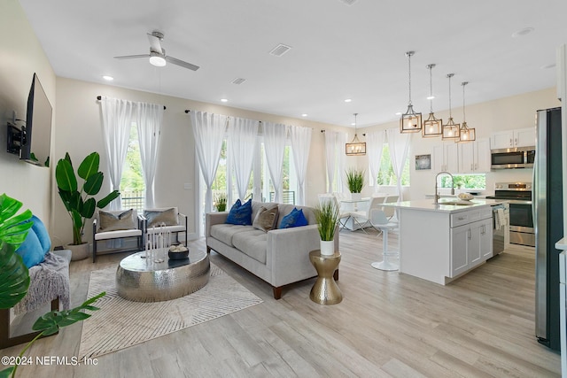 living room featuring sink, ceiling fan, and light hardwood / wood-style floors