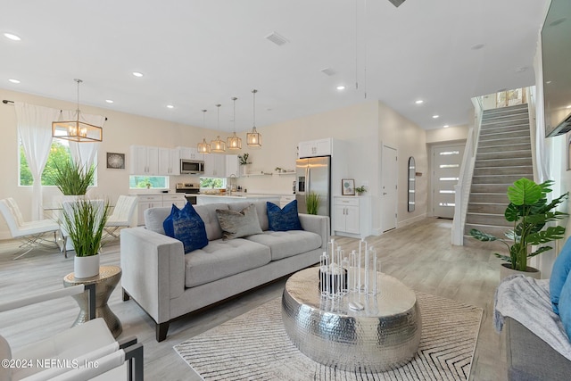 living room with sink, light wood-type flooring, and a notable chandelier