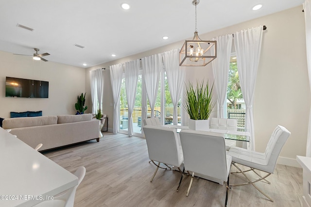 dining space featuring ceiling fan with notable chandelier and light wood-type flooring