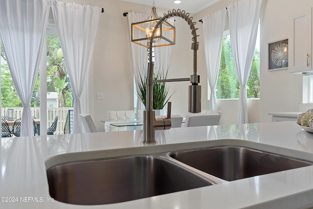 room details featuring a notable chandelier, white cabinetry, and decorative light fixtures