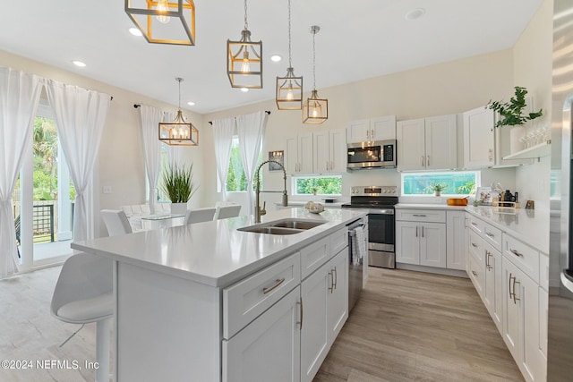 kitchen with sink, white cabinets, a center island with sink, pendant lighting, and appliances with stainless steel finishes