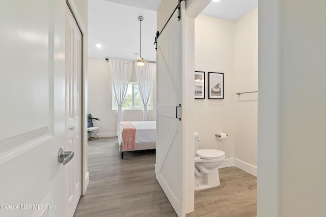 bathroom featuring toilet, hardwood / wood-style flooring, and ceiling fan