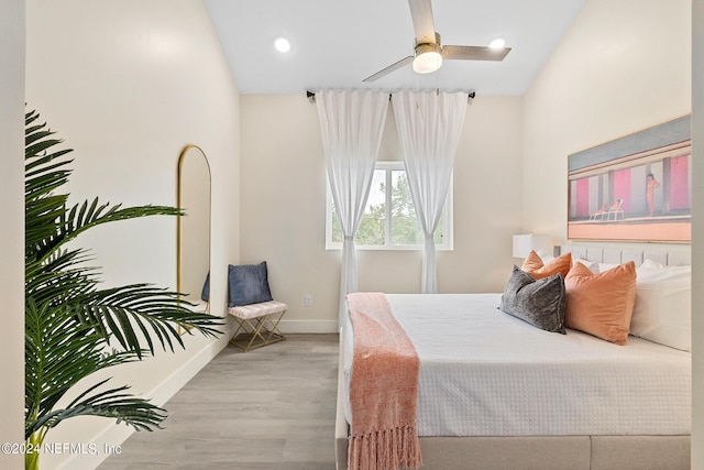 bedroom with ceiling fan, vaulted ceiling, and light wood-type flooring