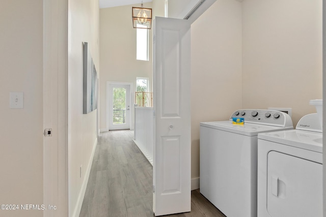 clothes washing area with an inviting chandelier, separate washer and dryer, and light hardwood / wood-style floors