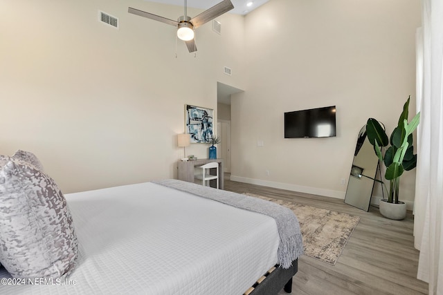 bedroom featuring a high ceiling, light wood-type flooring, and ceiling fan