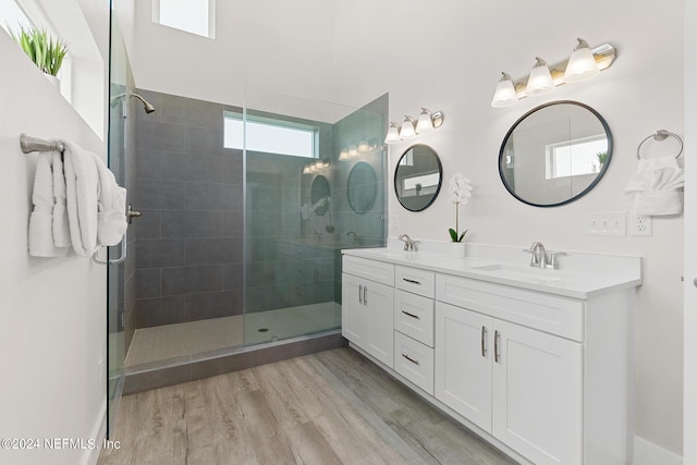 bathroom featuring hardwood / wood-style flooring, tiled shower, and vanity