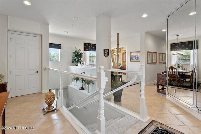 hallway with a notable chandelier and light tile patterned flooring