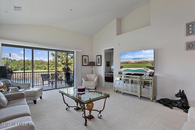 carpeted living room featuring a water view and high vaulted ceiling