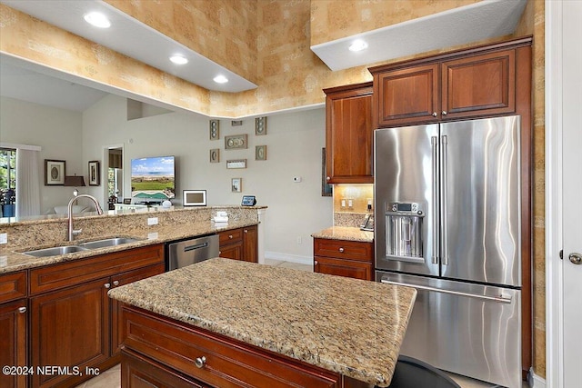 kitchen featuring light stone countertops, appliances with stainless steel finishes, backsplash, vaulted ceiling, and sink