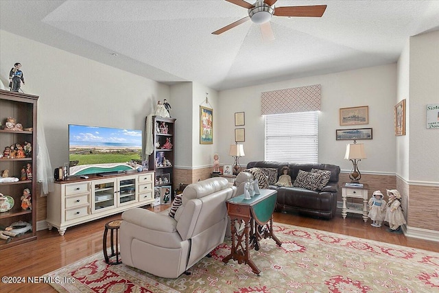 living room with ceiling fan, wood-type flooring, a textured ceiling, and vaulted ceiling